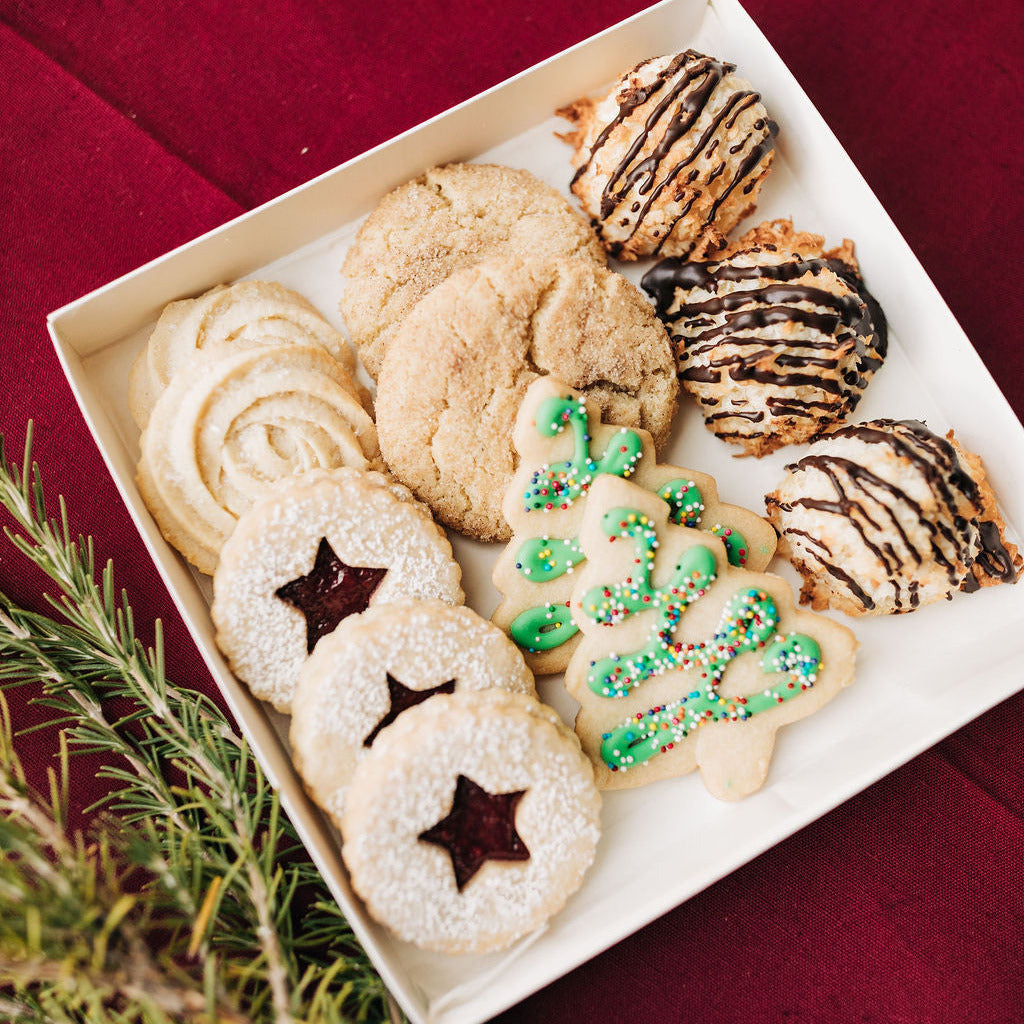 Assorted cookies on a white plate with a red background.