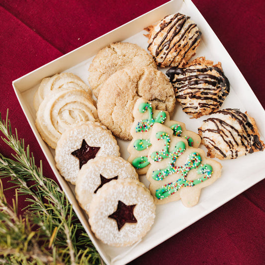 Assorted cookies on a white plate with a red background.