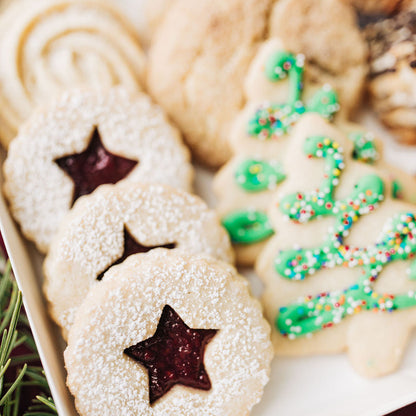 Assorted cookies including star-shaped and christmas decorated ones on a tray.