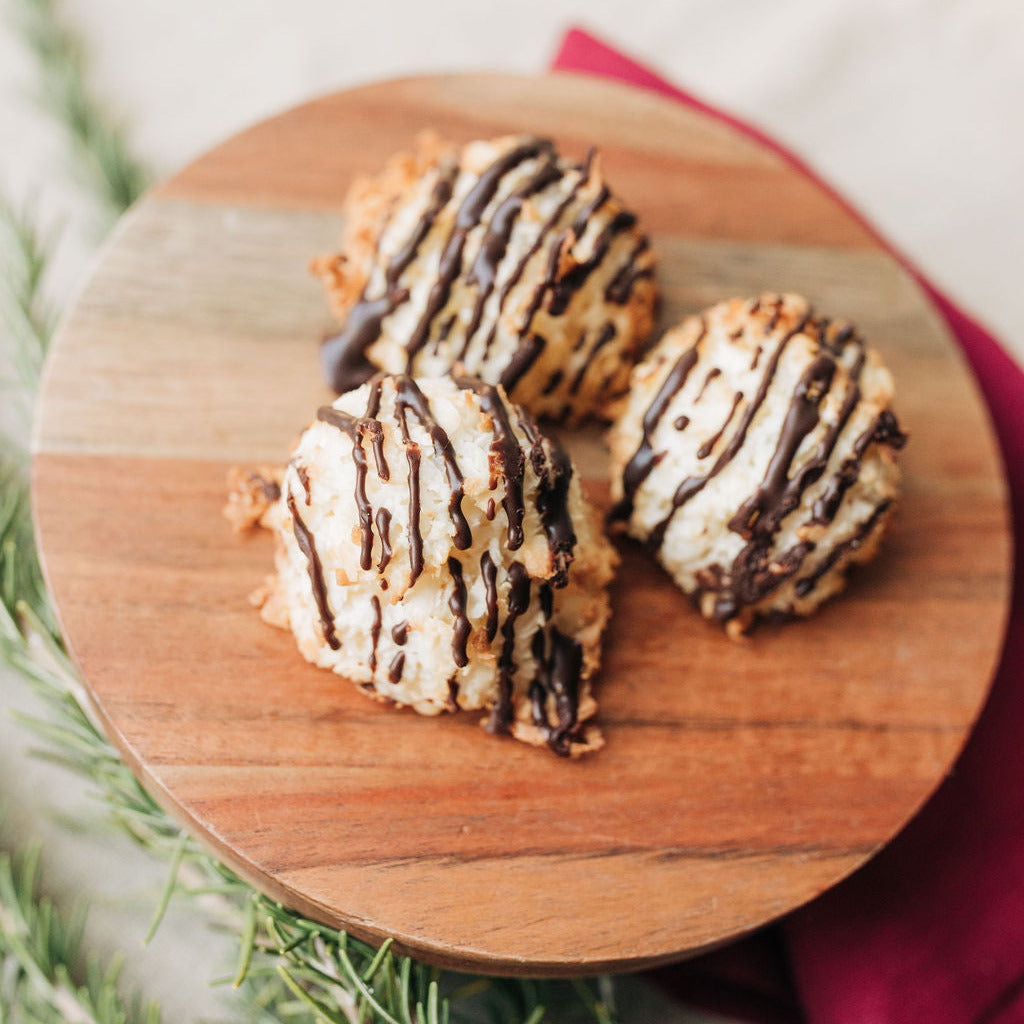 Three cookies with chocolate drizzle on a wooden board with a blurred background